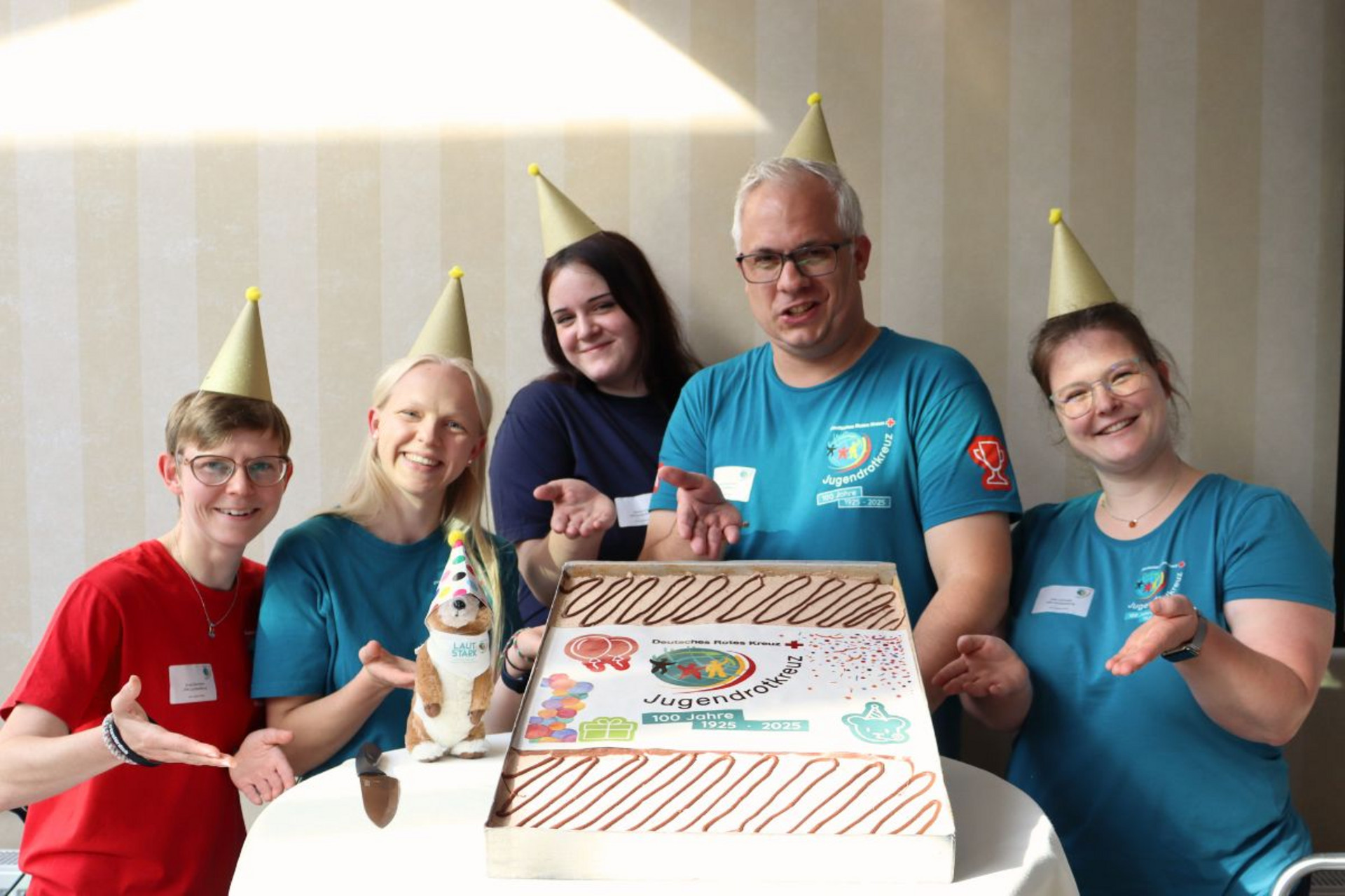 Aktuelles - Teaserbild Die JRK-Landesleitung präsentiert eine Jubiläumstorte zum 100-Jährigen Bestehen des Jugendrotkreuz.