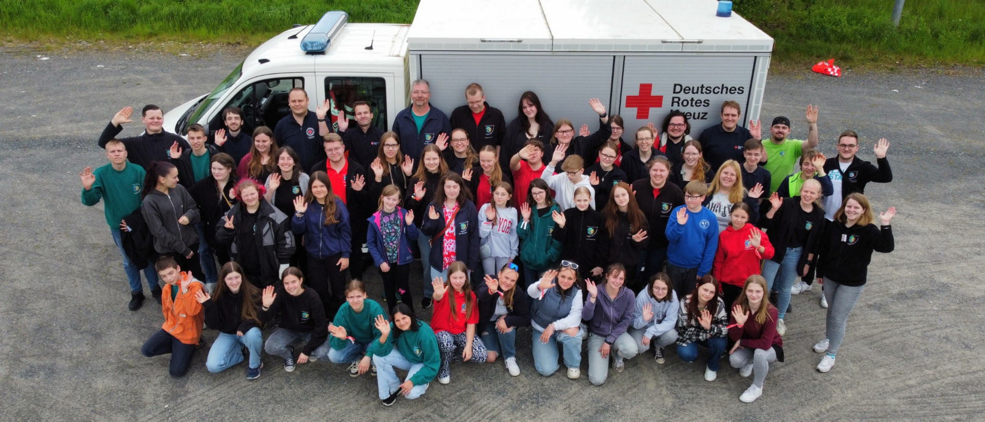 Gruppenfoto von Teilnehmenden bei ‚Abenteuer Menschlichkeit‘ vor DRK-Fahrzeug.
