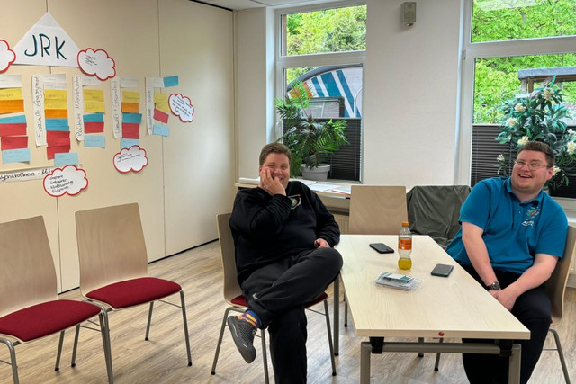 Zwei Teamende eines Junior-Gruppenleitungskurs sitzen im Seminarraum an einem Tisch.
