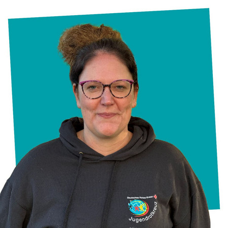 jrk-nds_jrk-landesgeschaeftsstelle_catharina-barkowsky Porträt einer lächelnden Kontaktperson des Jugendrotkreuzes Niedersachsen in einem schwarzen JRK-Hoodie
