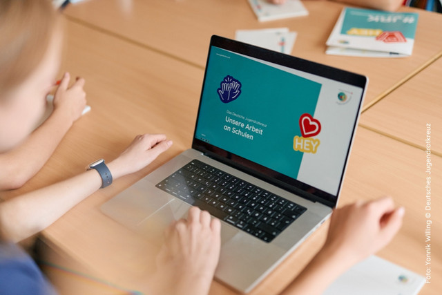 JRK-Mitglieder an einem Laptop mit einer Präsentation im JRK-Design.