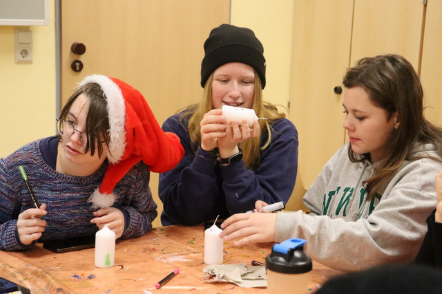 Jugendliche gestalten beim Winterzauber Kerzen.