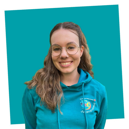 jrk-nds_jrk-landesgeschaeftsstelle_pia-sander Porträt einer lächelnden Kontaktperson des Jugendrotkreuzes Niedersachsen in einem blauen JRK-T-Shirt.