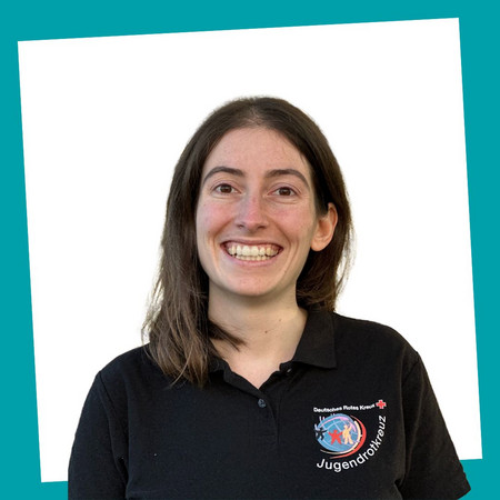 jrk-nds_jrk-landesgeschaeftsstelle_sonja-bakes_02 Porträt einer lächelnden Kontaktperson des Jugendrotkreuzes Niedersachsen in einem schwarzen JRK-T-Shirt.