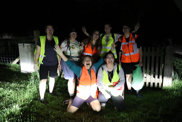 Eine JRK-Gruppe mit Warnwesten ist im Dunkeln beim Nachtorientierungslauf unterwegs.