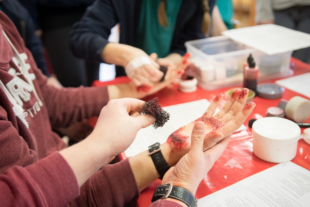 Teilnehmende schminken realistische Wunden in einem Kurs der Notfalldarstellung.