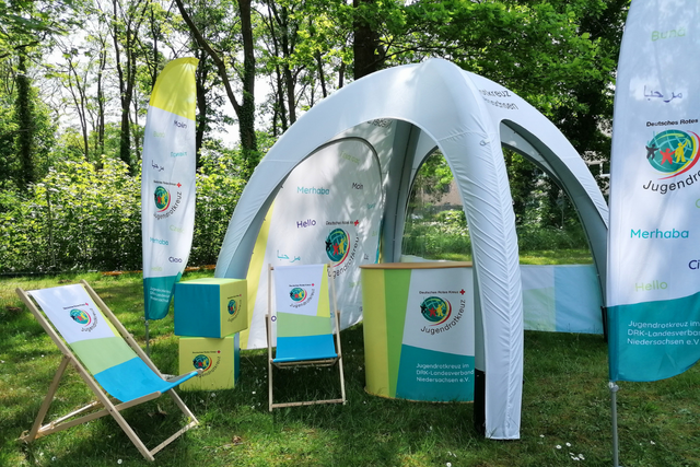 Der Pop-Up Store des JRK Niedersachsen mit einem Zelt, einer Theke, Beachflags, Liegestühlen und Sitzwürfeln.
