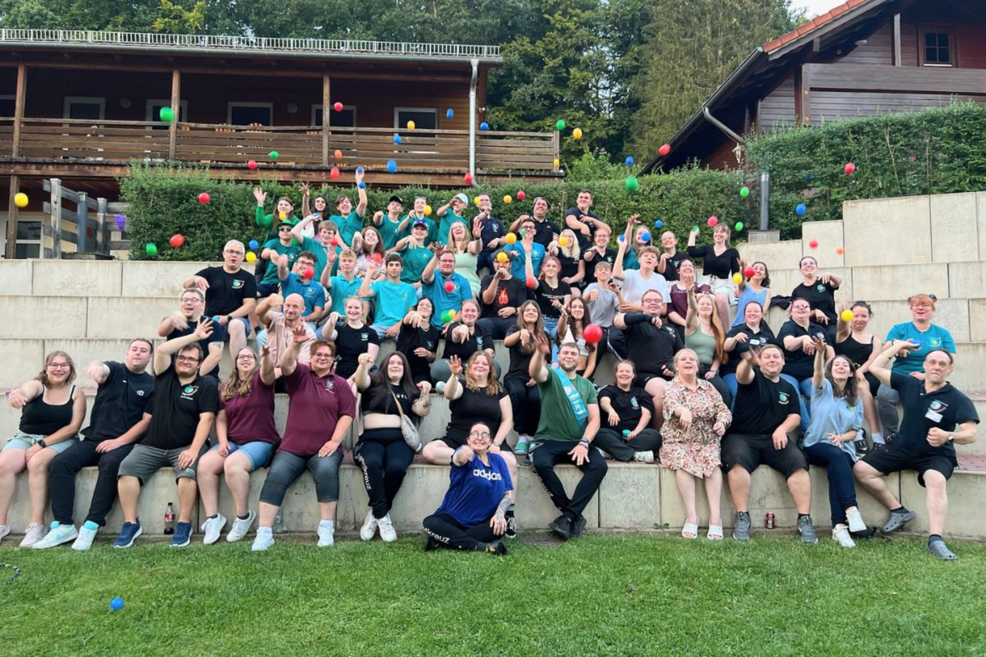 Veranstaltungen - Teaserbild Auf einem Gruppenbild bei einem JRK-Event werfen die Teilnehmenden bunte Bälle Richtung Kamera.